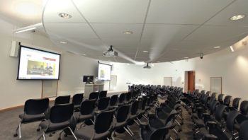 Large lecture hall with screens and furniture