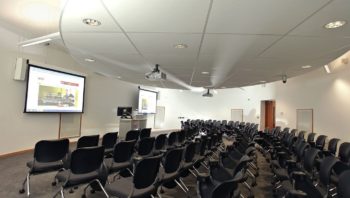 Large lecture hall with screens and furniture